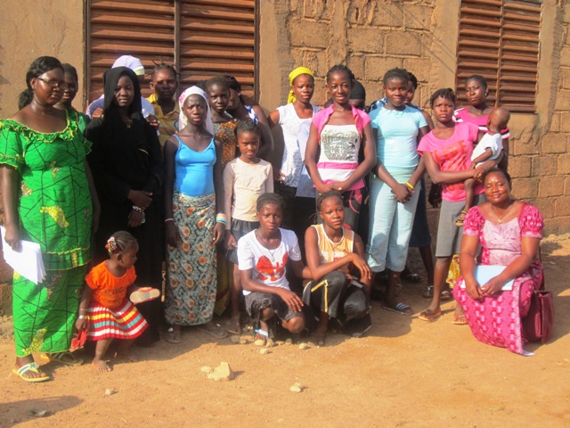 Photo de famille des filles sensibilisées sur la planification familiale avec les 2 éducatrices de l'association ADEP à gauche et droite.